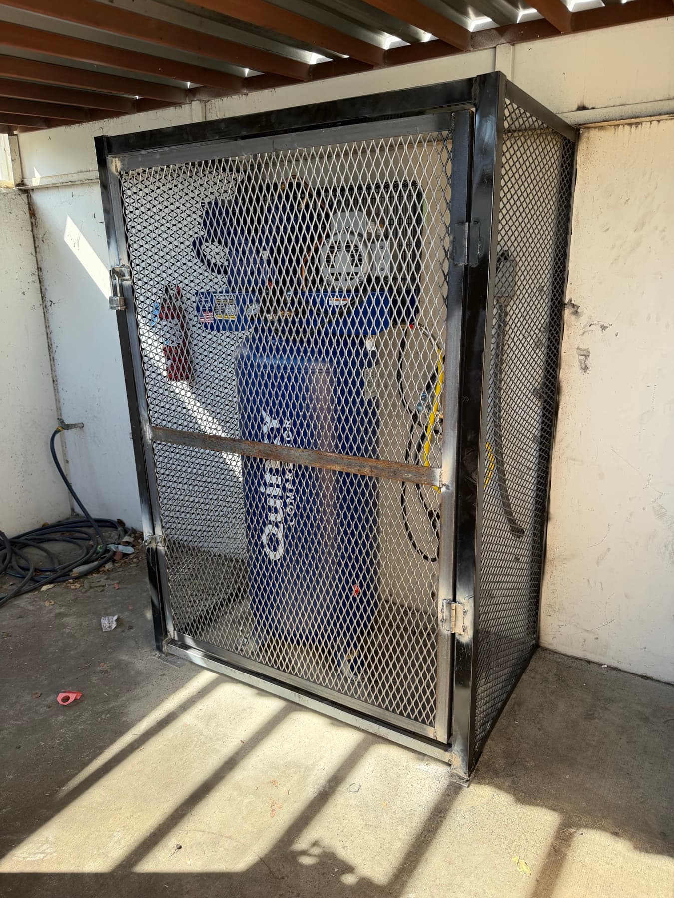 Expanded metal equipment cage built by Empire Fence for a secured utility area