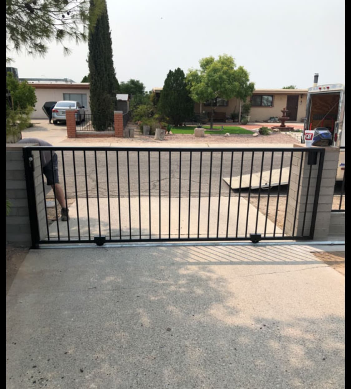 Black residential sliding drive gate installed across a driveway opening