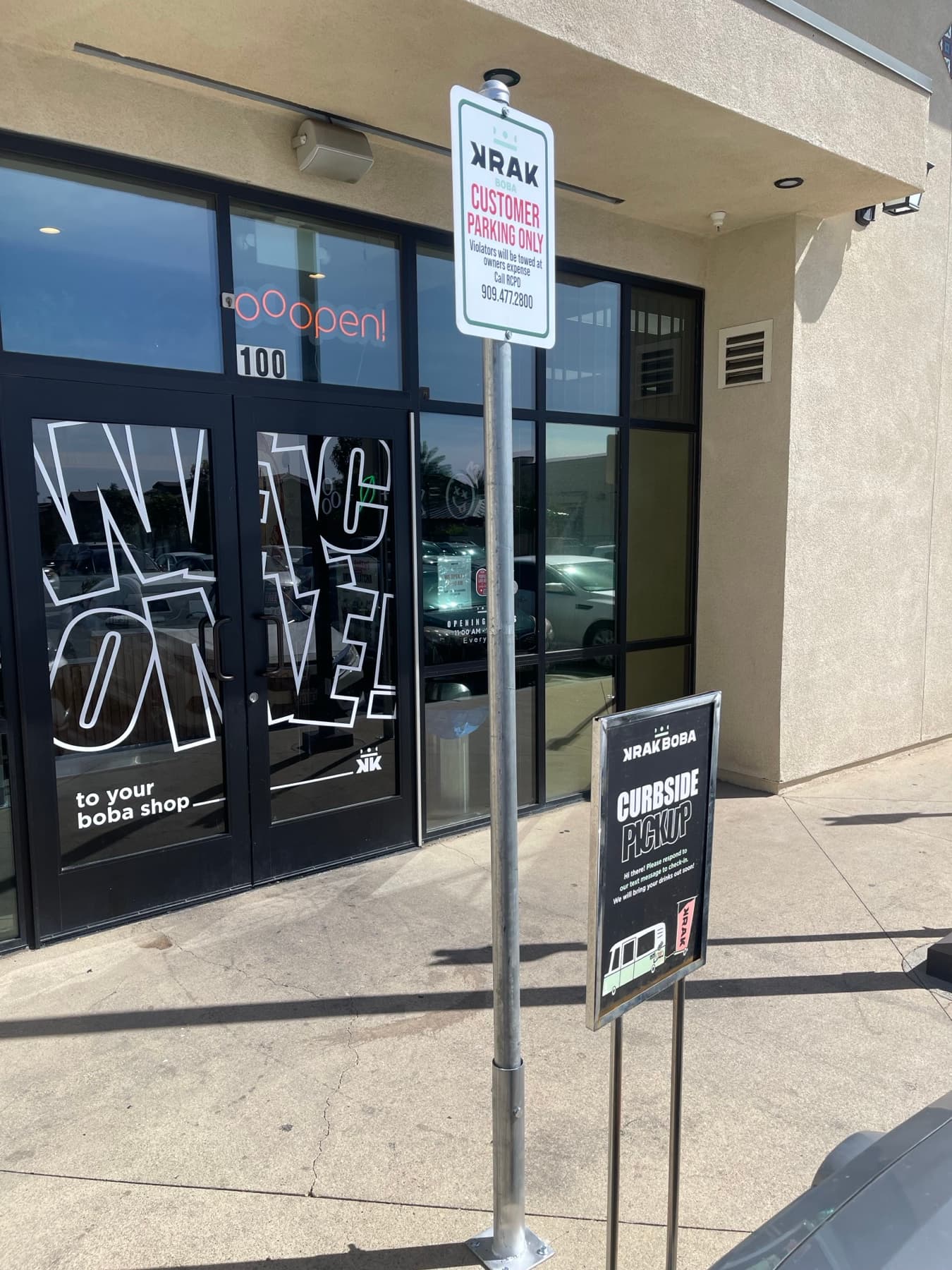 Customer parking sign post installation in front of a commercial storefront