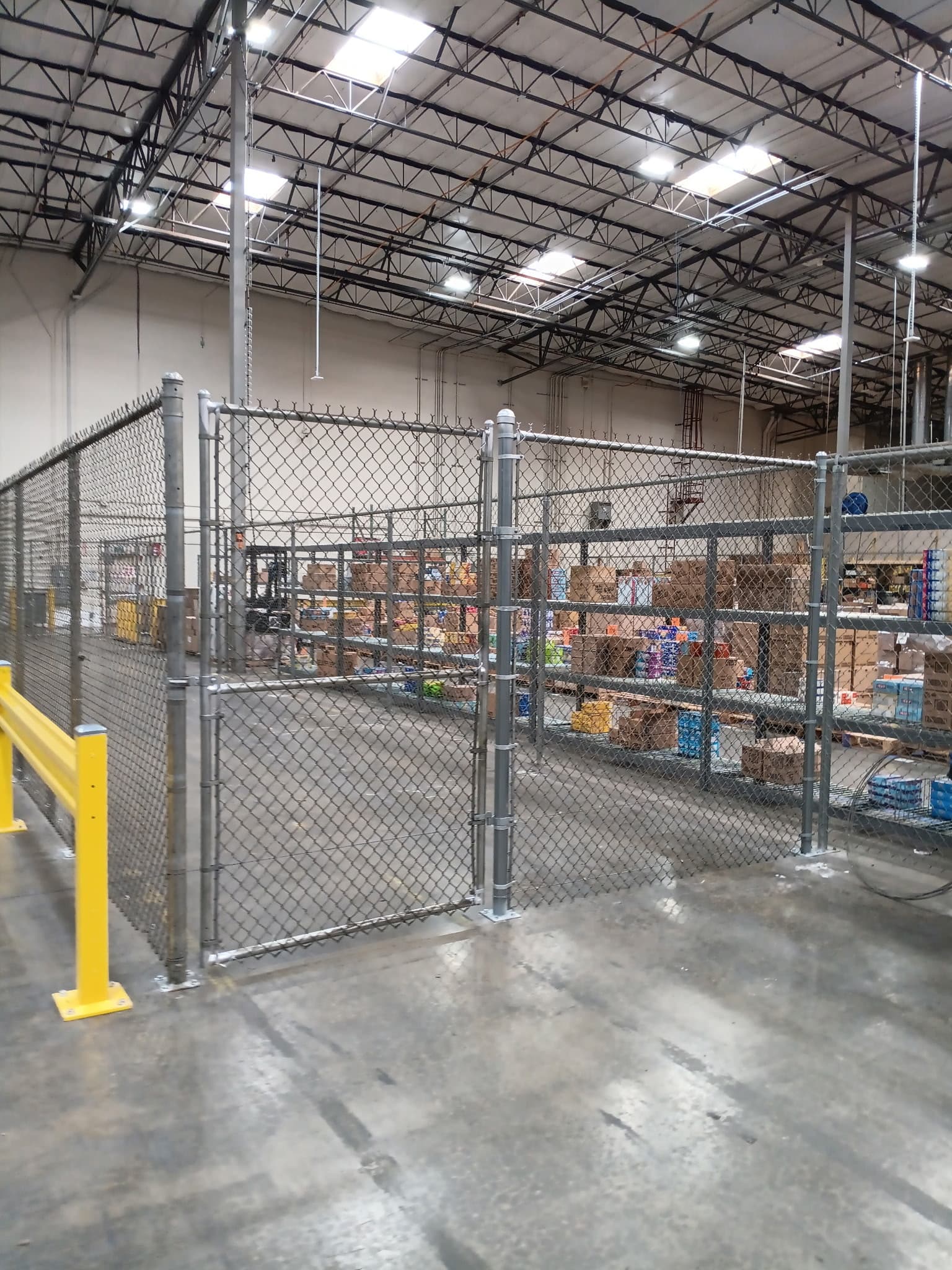 Warehouse chain link enclosure with walk gate access inside an industrial facility