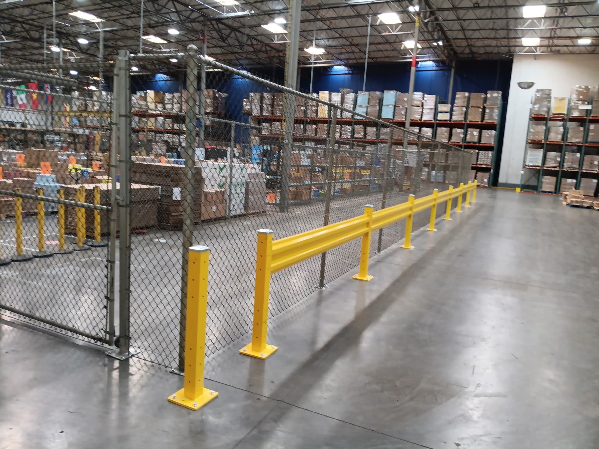 Warehouse chain link safety enclosure with yellow guardrail protection