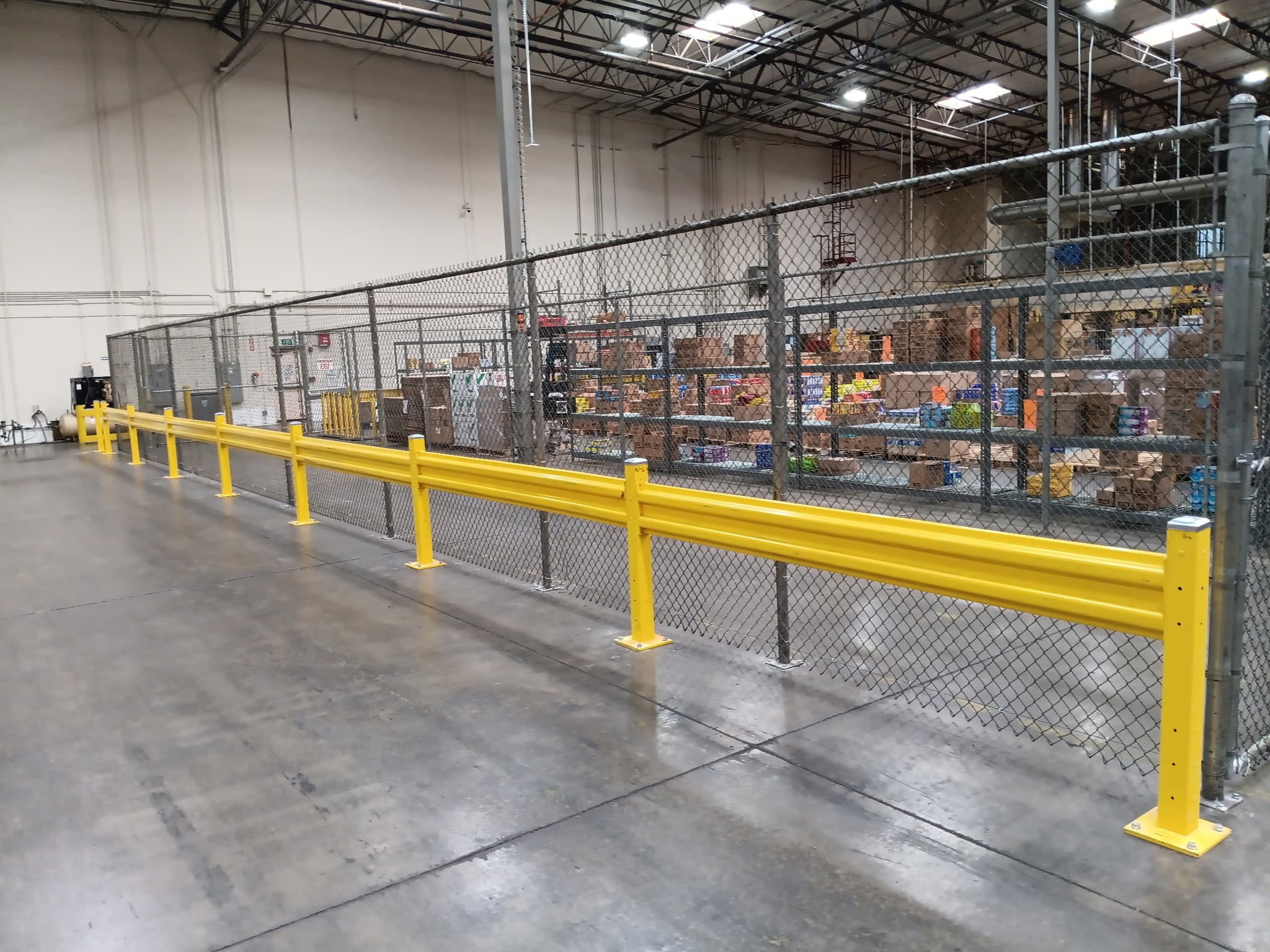 Side run of a warehouse chain link enclosure with safety rail protection