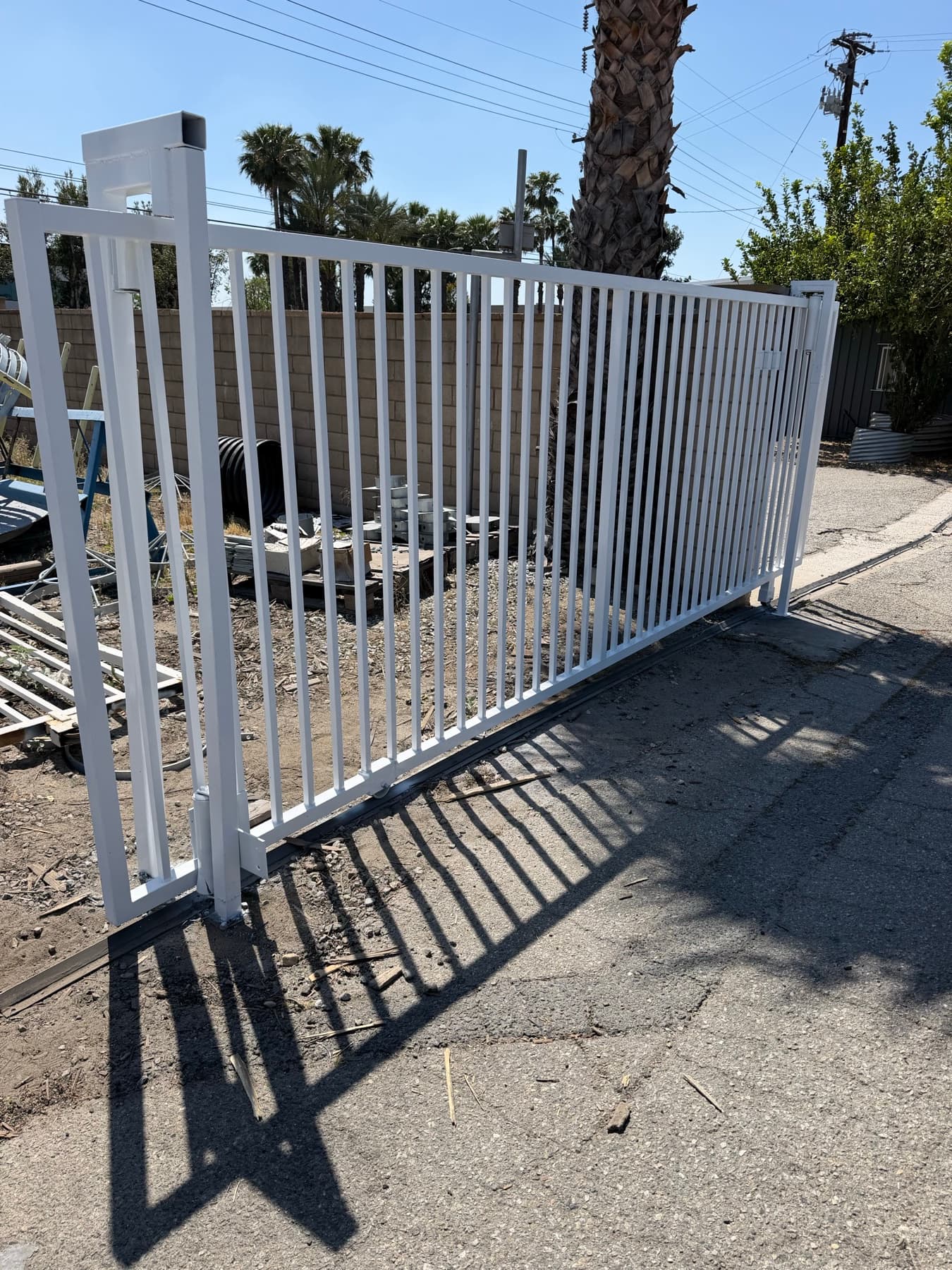 Open white commercial sliding gate showing the full track and fence line
